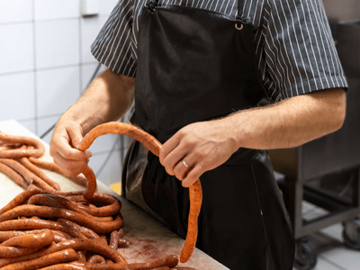 Un charcutier préparer des merguez dans la boucherie Sarthou